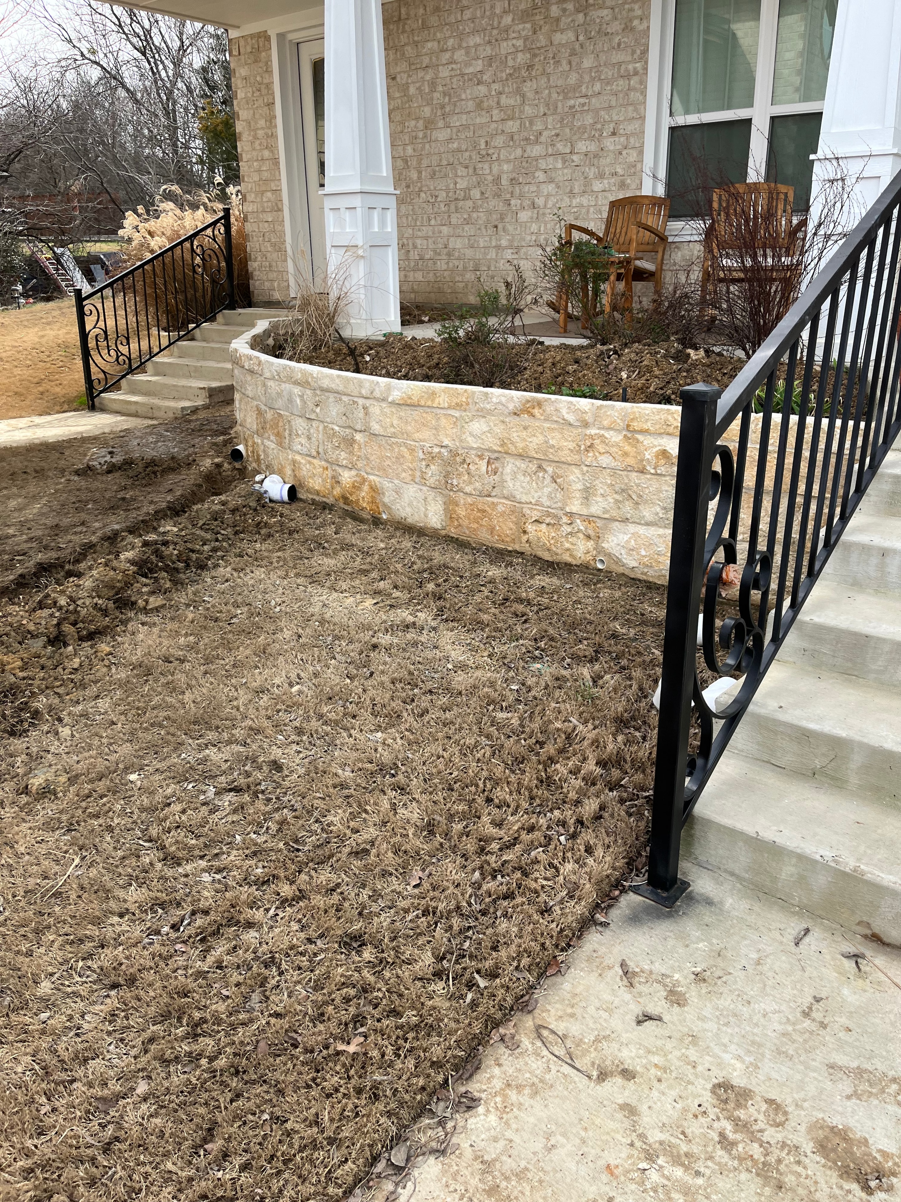 Drainage pipe and gravel being installed behind a retaining wall